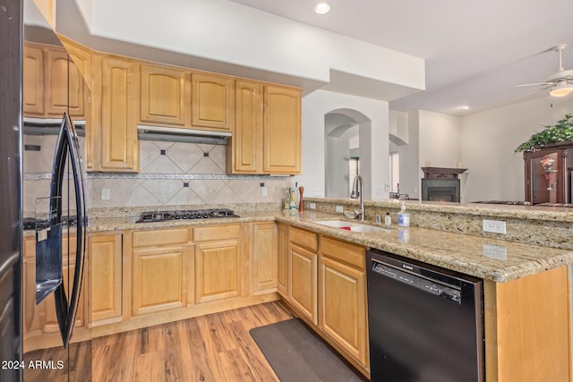 kitchen with light stone countertops, sink, light hardwood / wood-style flooring, and black appliances