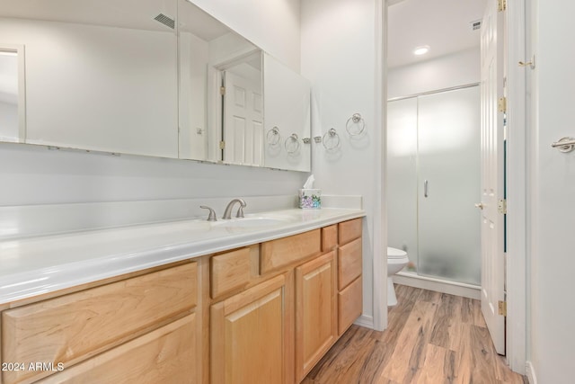 bathroom featuring vanity, wood-type flooring, an enclosed shower, and toilet