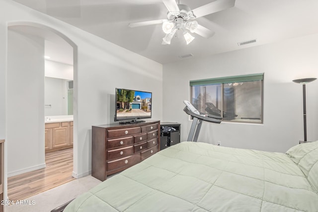 bedroom featuring ceiling fan, ensuite bath, and light hardwood / wood-style flooring