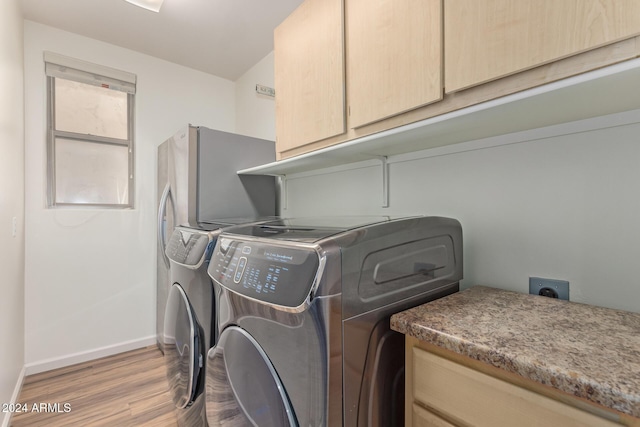 laundry area with cabinets, light hardwood / wood-style flooring, and washing machine and clothes dryer