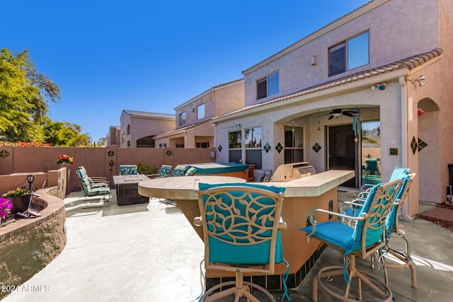 view of patio with ceiling fan, a bar, and exterior kitchen