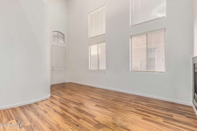 unfurnished room featuring light wood-type flooring and a high ceiling