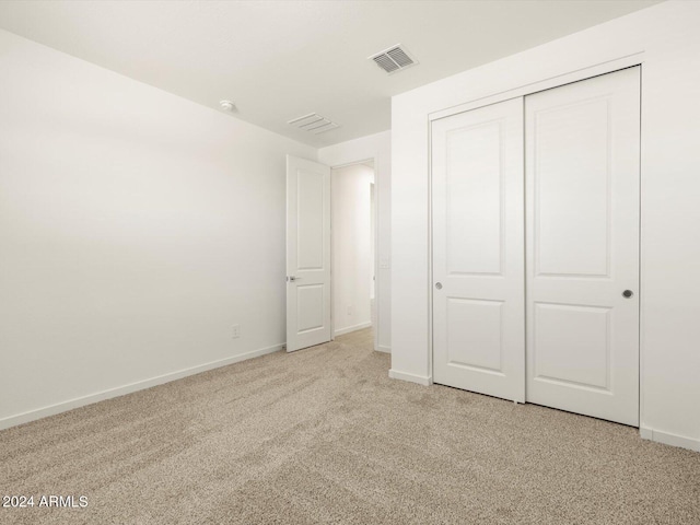 unfurnished bedroom featuring light colored carpet and a closet