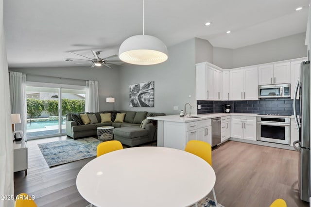 1057 W Laurel Ave, Gilbert, AZ 85233 - kitchen with stainless steel appliances, open floor plan, lofted ceiling, backsplash, and white cabinets