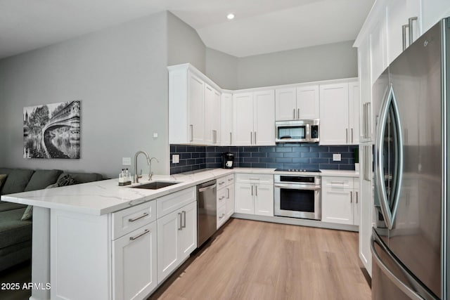 1057 W Laurel Ave, Gilbert, AZ 85233 - kitchen featuring appliances with stainless steel finishes, white cabinetry, a peninsula, light wood-style flooring, and light stone counters