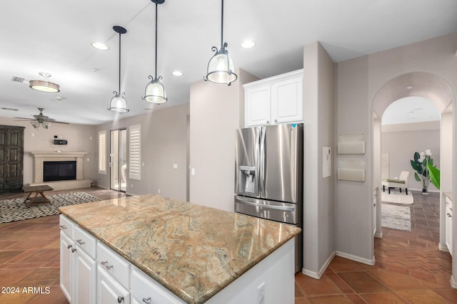 kitchen featuring light stone counters, white cabinets, a kitchen island, pendant lighting, and ceiling fan