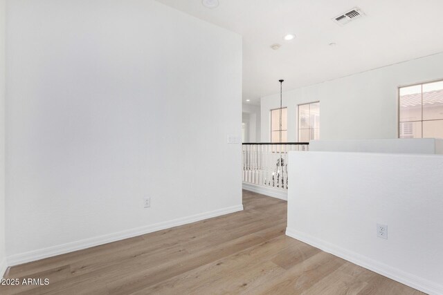 empty room with ceiling fan, light hardwood / wood-style floors, and a barn door