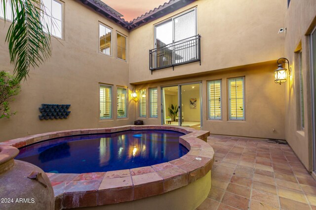 pool at dusk with an in ground hot tub and a patio area