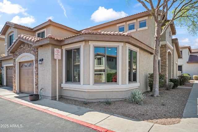 view of front of home featuring a tile roof, stucco siding, and an attached garage