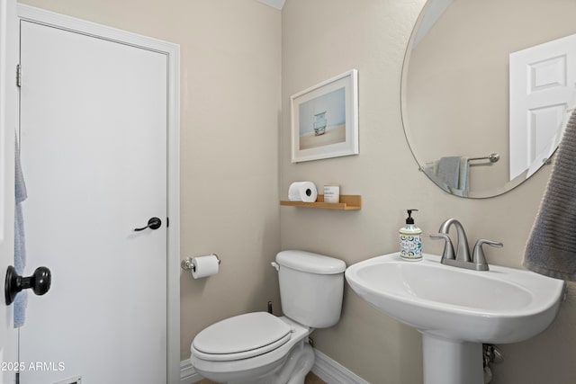 bathroom with baseboards, toilet, and a sink