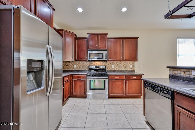 kitchen featuring tasteful backsplash, recessed lighting, light tile patterned floors, appliances with stainless steel finishes, and dark countertops
