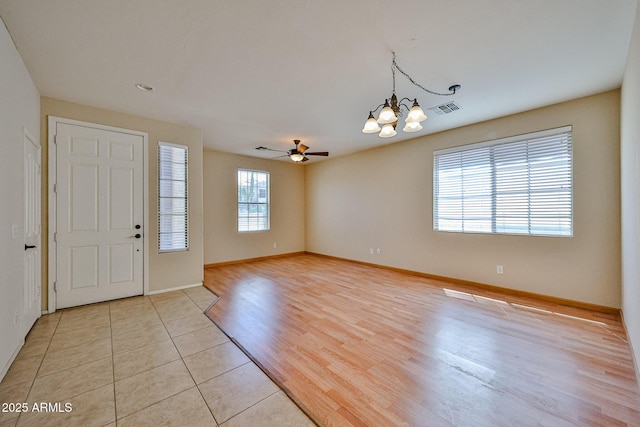 entryway with light tile patterned flooring, visible vents, baseboards, and ceiling fan with notable chandelier