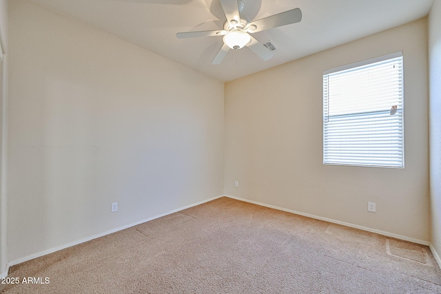 carpeted empty room featuring baseboards, visible vents, and a ceiling fan