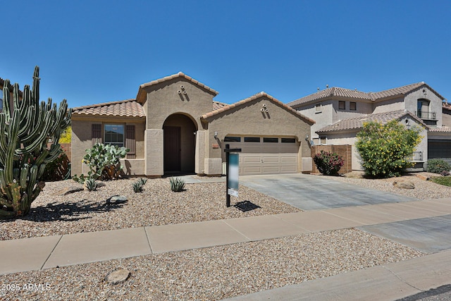 mediterranean / spanish-style home featuring driveway, a garage, stucco siding, and a tiled roof