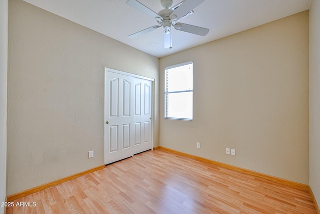 unfurnished bedroom with baseboards, wood finished floors, a ceiling fan, and a closet