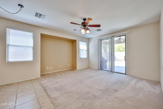 empty room with visible vents, ceiling fan, and baseboards