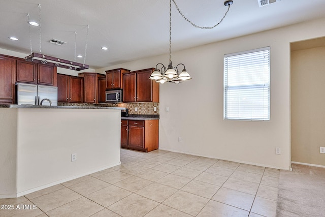 kitchen featuring decorative backsplash, visible vents, stainless steel appliances, an inviting chandelier, and hanging light fixtures