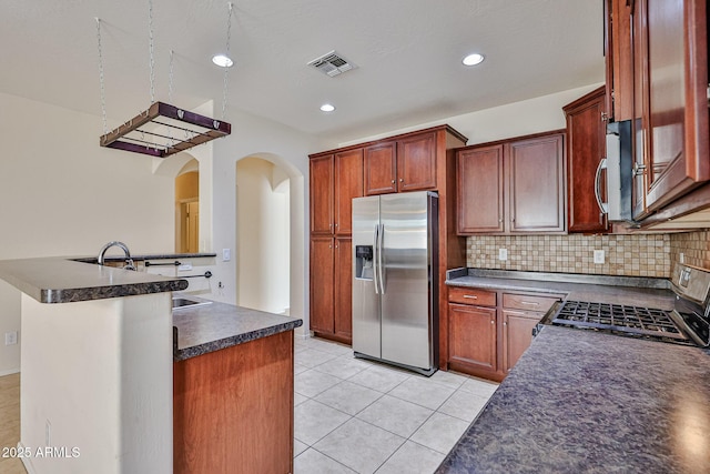 kitchen featuring stainless steel appliances, decorative backsplash, visible vents, dark countertops, and arched walkways