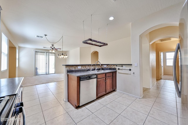 kitchen featuring arched walkways, appliances with stainless steel finishes, dark countertops, ceiling fan, and a sink