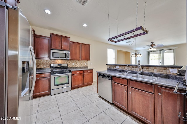 kitchen with decorative backsplash, appliances with stainless steel finishes, dark countertops, a sink, and visible vents