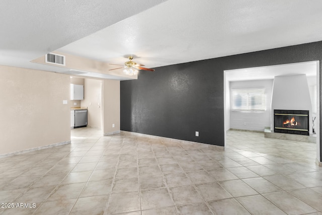 unfurnished living room with ceiling fan, light tile patterned floors, and a textured ceiling