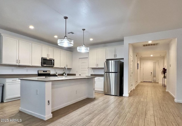 kitchen featuring light wood-type flooring, visible vents, dark countertops, white cabinetry, and appliances with stainless steel finishes