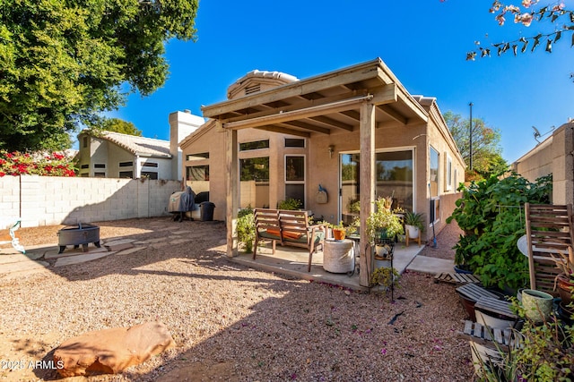 back of property with a patio area and an outdoor living space with a fire pit