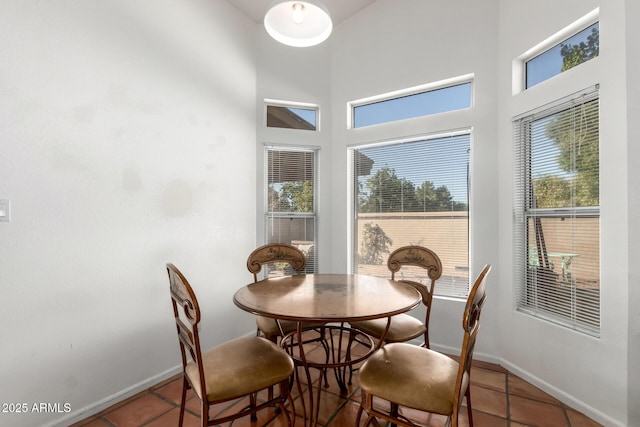 dining area featuring dark tile patterned flooring and a high ceiling