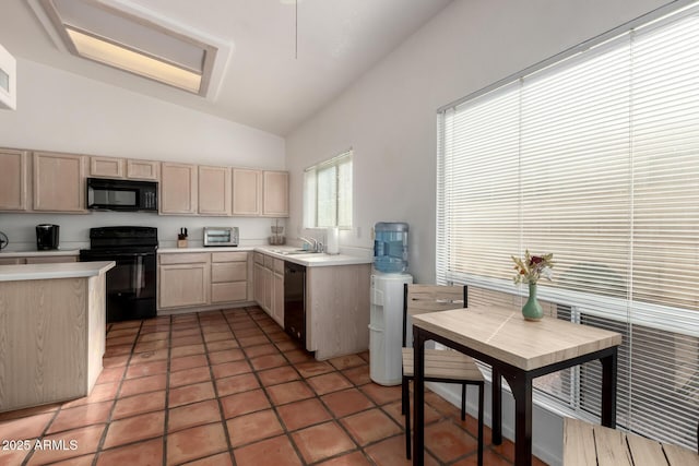 kitchen featuring vaulted ceiling, black appliances, sink, dark tile patterned floors, and light brown cabinetry