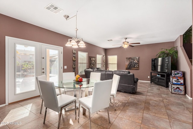 dining space featuring a healthy amount of sunlight, ceiling fan with notable chandelier, and french doors