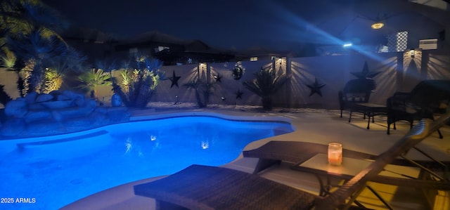 pool at night featuring a patio area