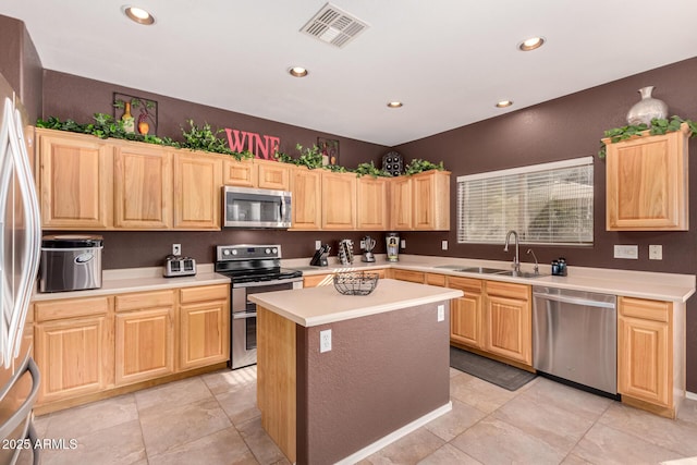 kitchen with light tile patterned floors, stainless steel appliances, light brown cabinets, a kitchen island, and sink