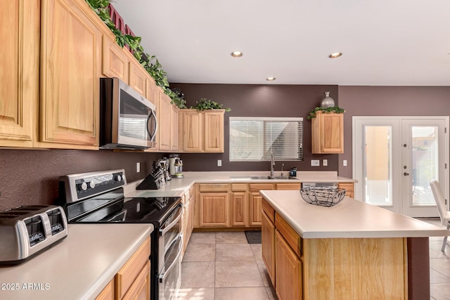 kitchen featuring appliances with stainless steel finishes, light tile patterned flooring, french doors, a kitchen island, and sink