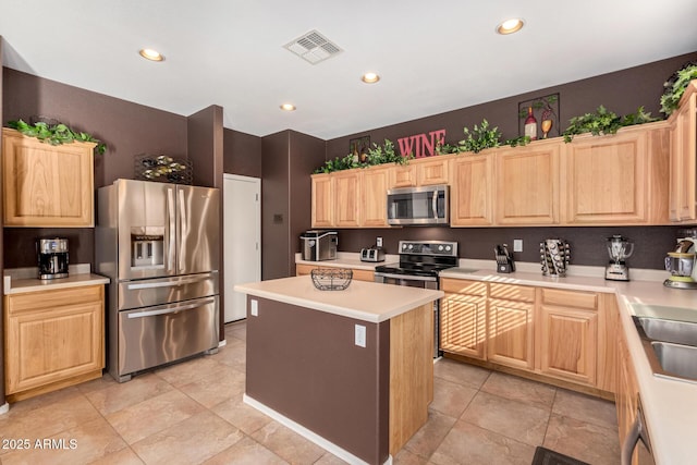 kitchen with light brown cabinets, light tile patterned floors, a center island, and stainless steel appliances