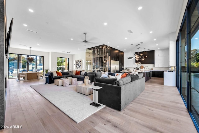 living room featuring light wood-type flooring and ceiling fan with notable chandelier