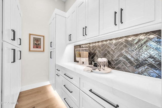 bar featuring light hardwood / wood-style floors, white cabinetry, and tasteful backsplash