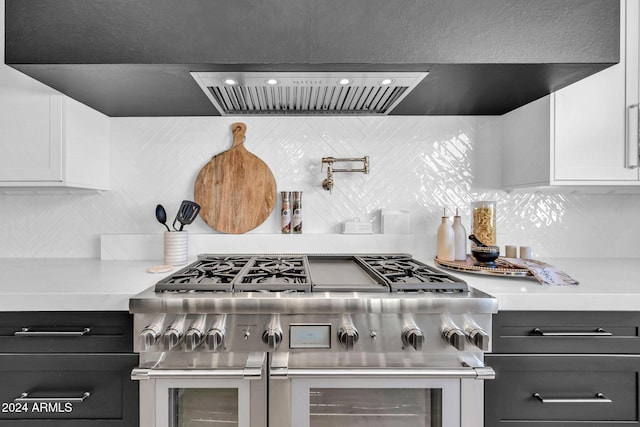 kitchen with range with two ovens, exhaust hood, white cabinets, light countertops, and decorative backsplash