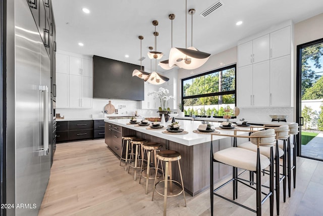 kitchen with stainless steel built in fridge, a center island, decorative light fixtures, and white cabinets