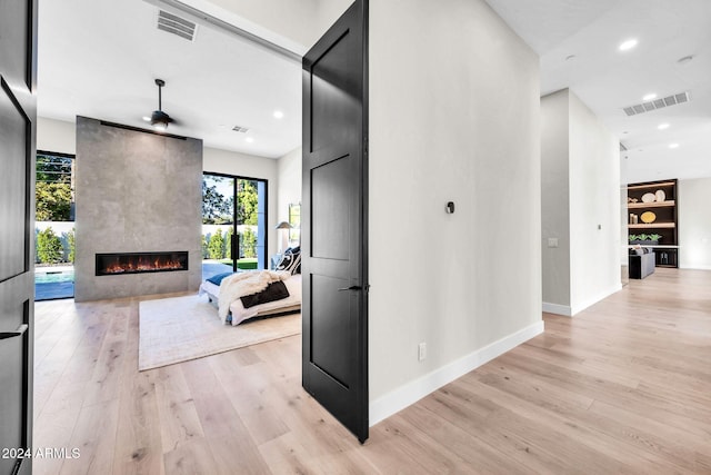 hall featuring light wood-type flooring, visible vents, baseboards, and recessed lighting