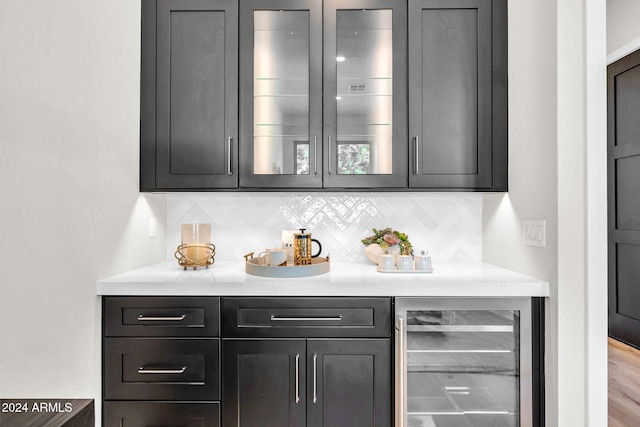 bar with tasteful backsplash, hardwood / wood-style flooring, and beverage cooler