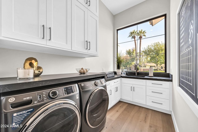 washroom featuring cabinets, washer and dryer, sink, and light wood-type flooring