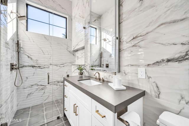 full bathroom featuring toilet, vanity, a marble finish shower, and tile walls