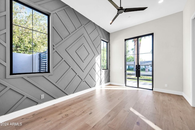 unfurnished room featuring an accent wall, a ceiling fan, baseboards, and wood finished floors