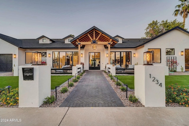 view of front facade featuring a yard, an outdoor living space, french doors, and stucco siding