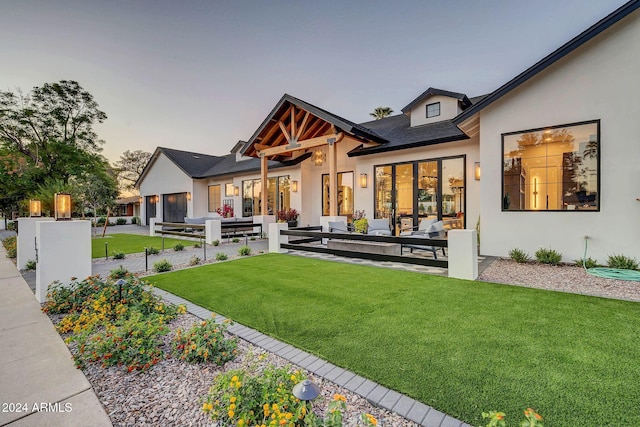 back house at dusk with a patio area, a lawn, and an outdoor hangout area