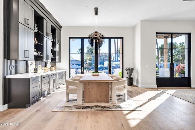 interior space featuring light wood finished floors, baseboards, a chandelier, and french doors