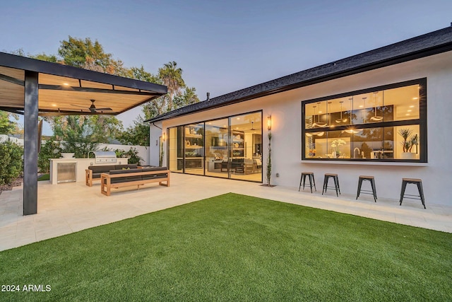 rear view of house with a yard, stucco siding, area for grilling, a ceiling fan, and a patio area