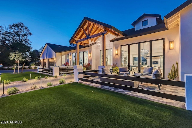 back of property featuring stucco siding, outdoor lounge area, and a yard