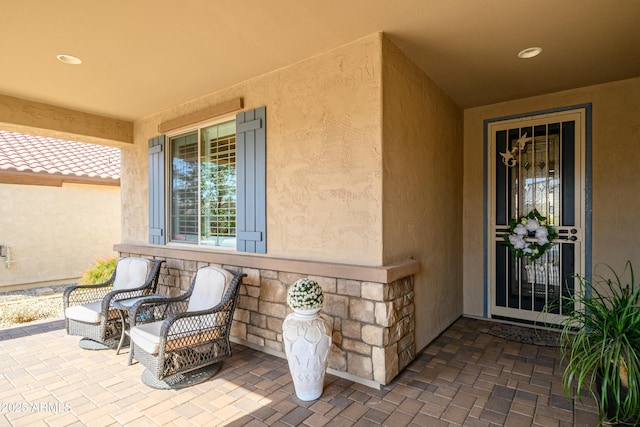 view of exterior entry featuring stone siding and stucco siding