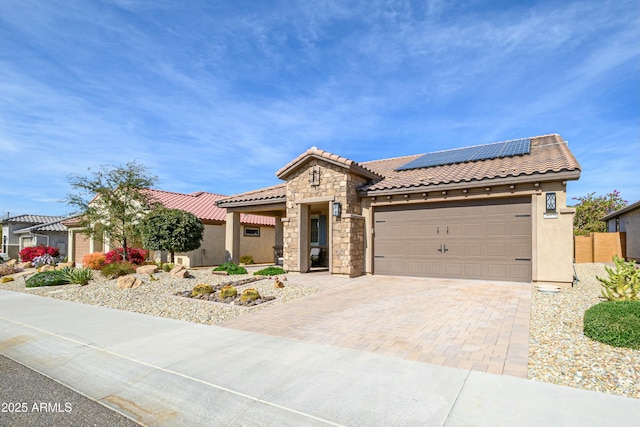 mediterranean / spanish home with decorative driveway, stucco siding, an attached garage, roof mounted solar panels, and a pergola